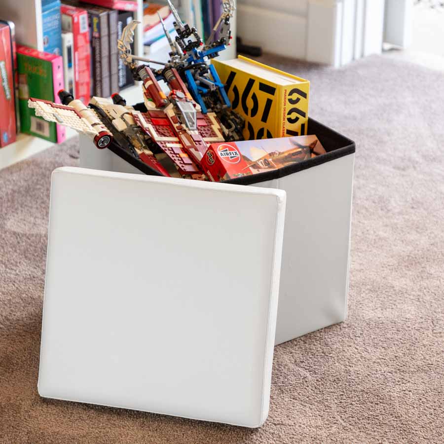 White Collapsible Ottoman in a living room filled with toys.