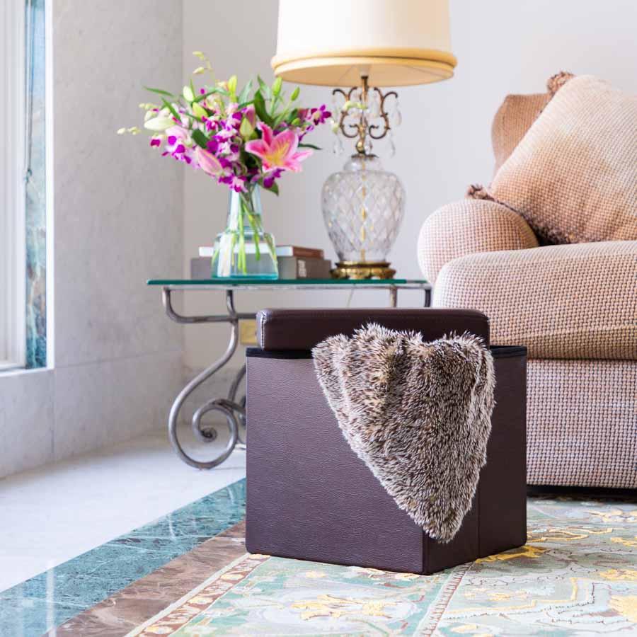 Open Brown Collapsible Ottoman with a blanket hanging out in a living room